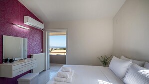 A bedroom with a bed, a vanity with a mirror, a window with a view, and a door leading to an outdoor area. - 10-Guest Countryside Villa with Barbecue (Heraklion)