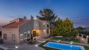 A modern house with a swimming pool, outdoor seating, and a large tree. - 10-Guest Countryside Villa with Barbecue (Heraklion)