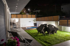 A modern outdoor patio with a swimming pool, lounge chairs, and a well-maintained lawn. - Modern Villa Vacation for 6 with Pool (Gouves)