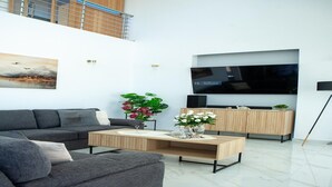 Ein modernes Wohnzimmer mit Sofa, Couchtisch, Fernseher und einer Pflanze.