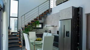 Eine moderne Küche mit Essbereich, Edelstahlgeräten und einer Treppe.