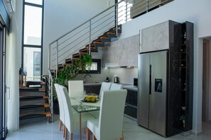 A modern kitchen with a dining area, stainless steel appliances, and a staircase. - Modern Villa Vacation for 6 with Pool (Gouves)