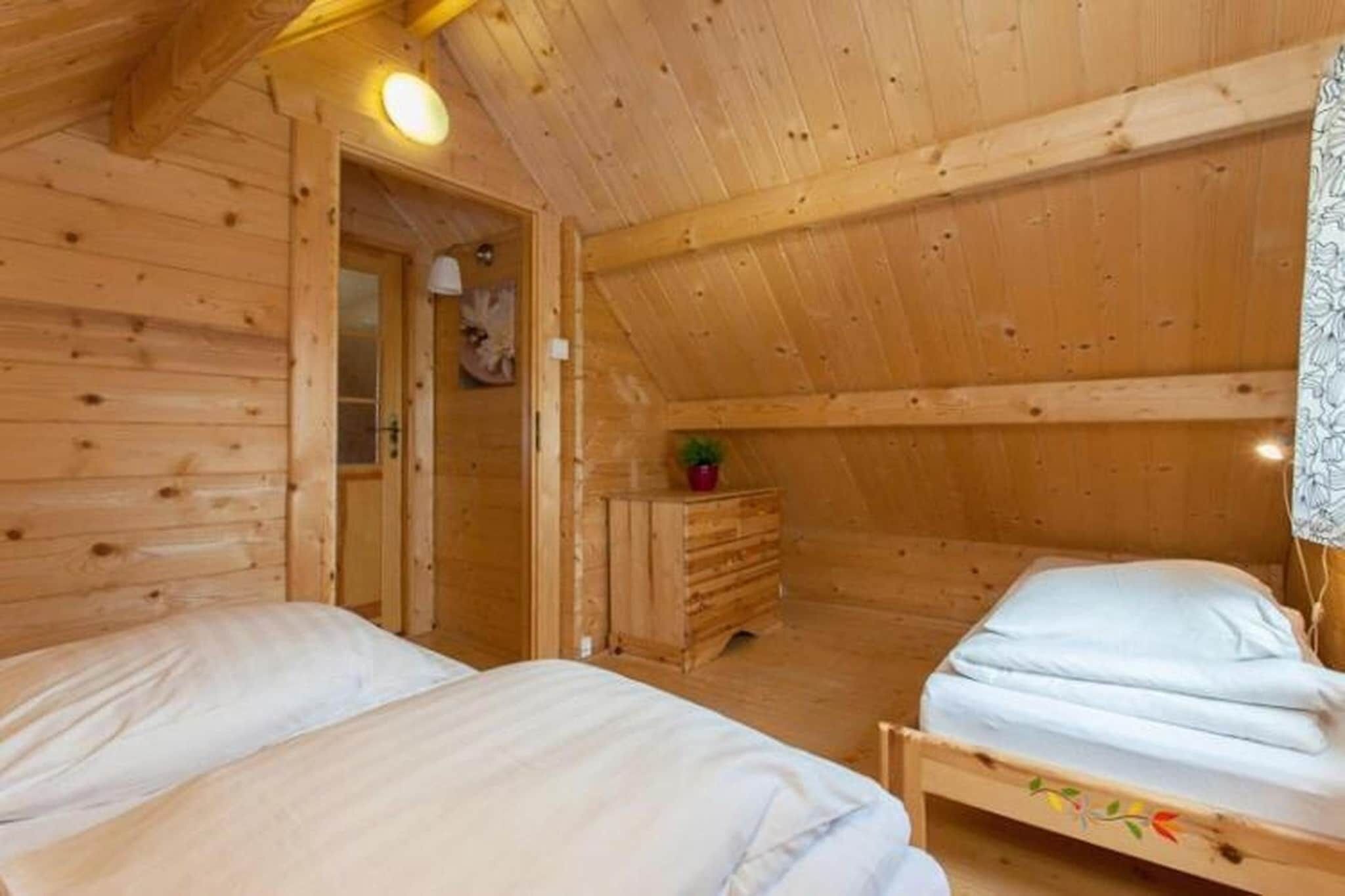 A wooden cabin room with two beds, a dresser, and a door leading to another room.