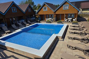 A swimming pool with lounge chairs and a covered patio area.
