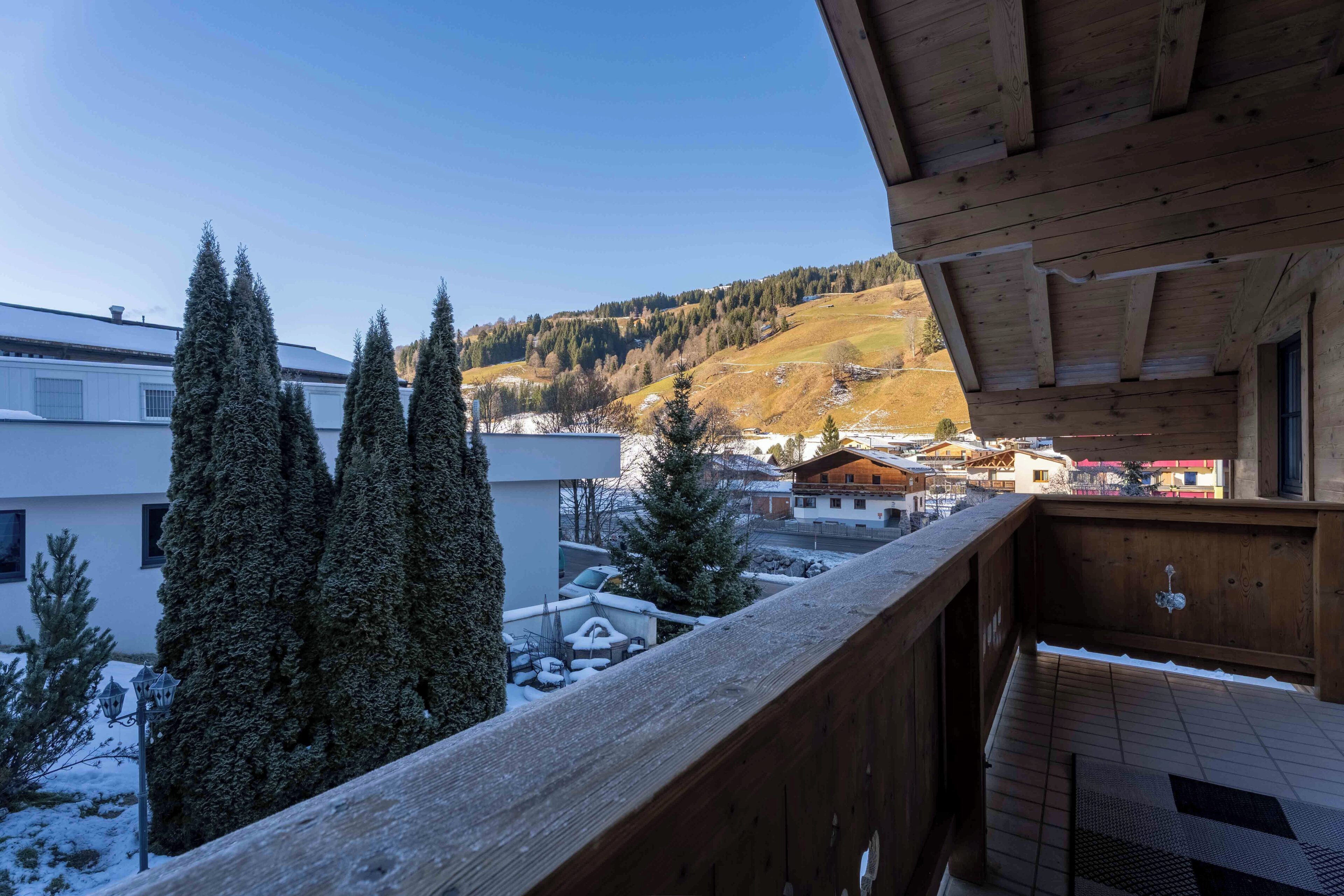 Un balcón de madera con vistas a árboles nevados y edificios.