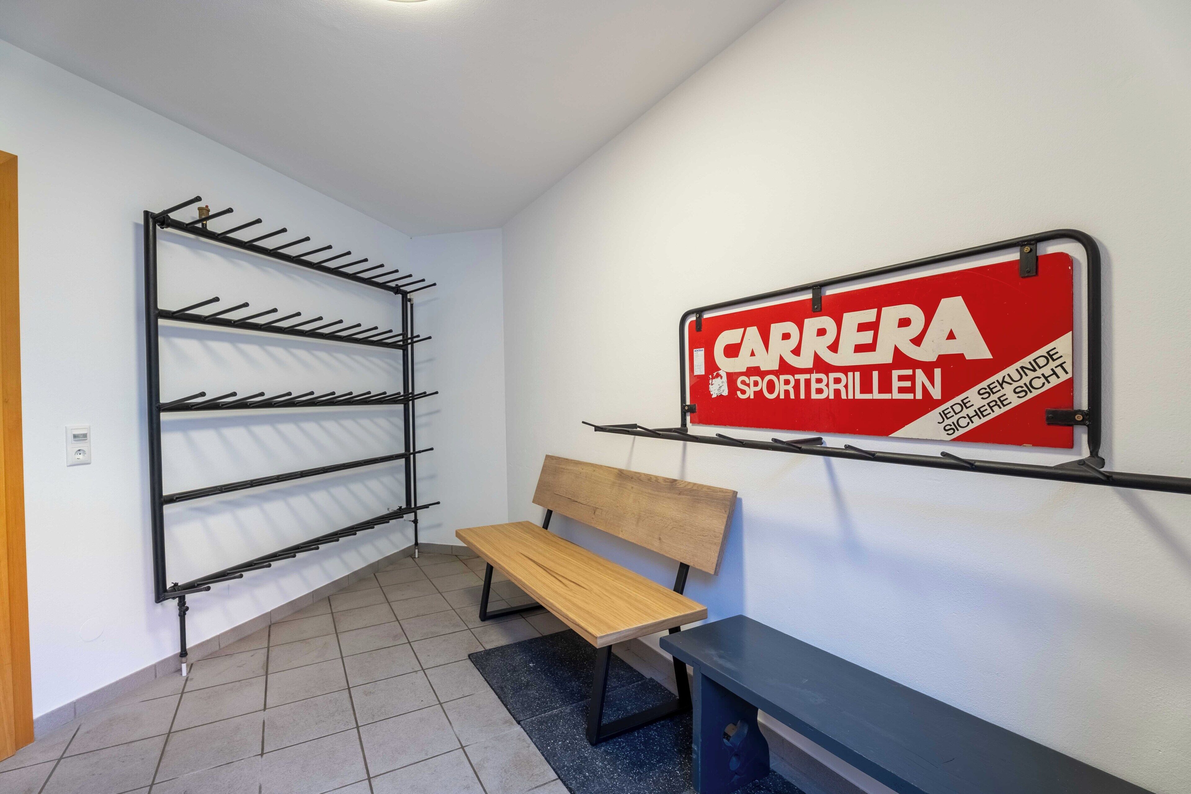 A hallway with a bench, a wall-mounted rack, and a sign.