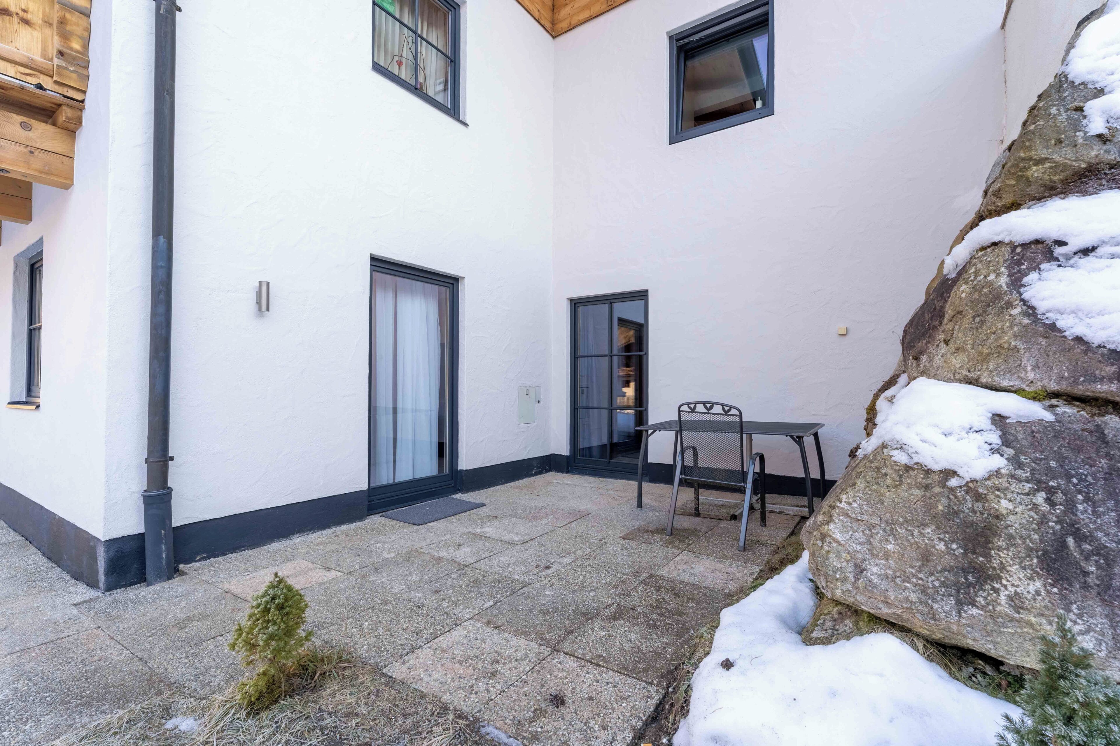 Un bâtiment doté d’une terrasse en pierre, d’une porte et d’une fenêtre.