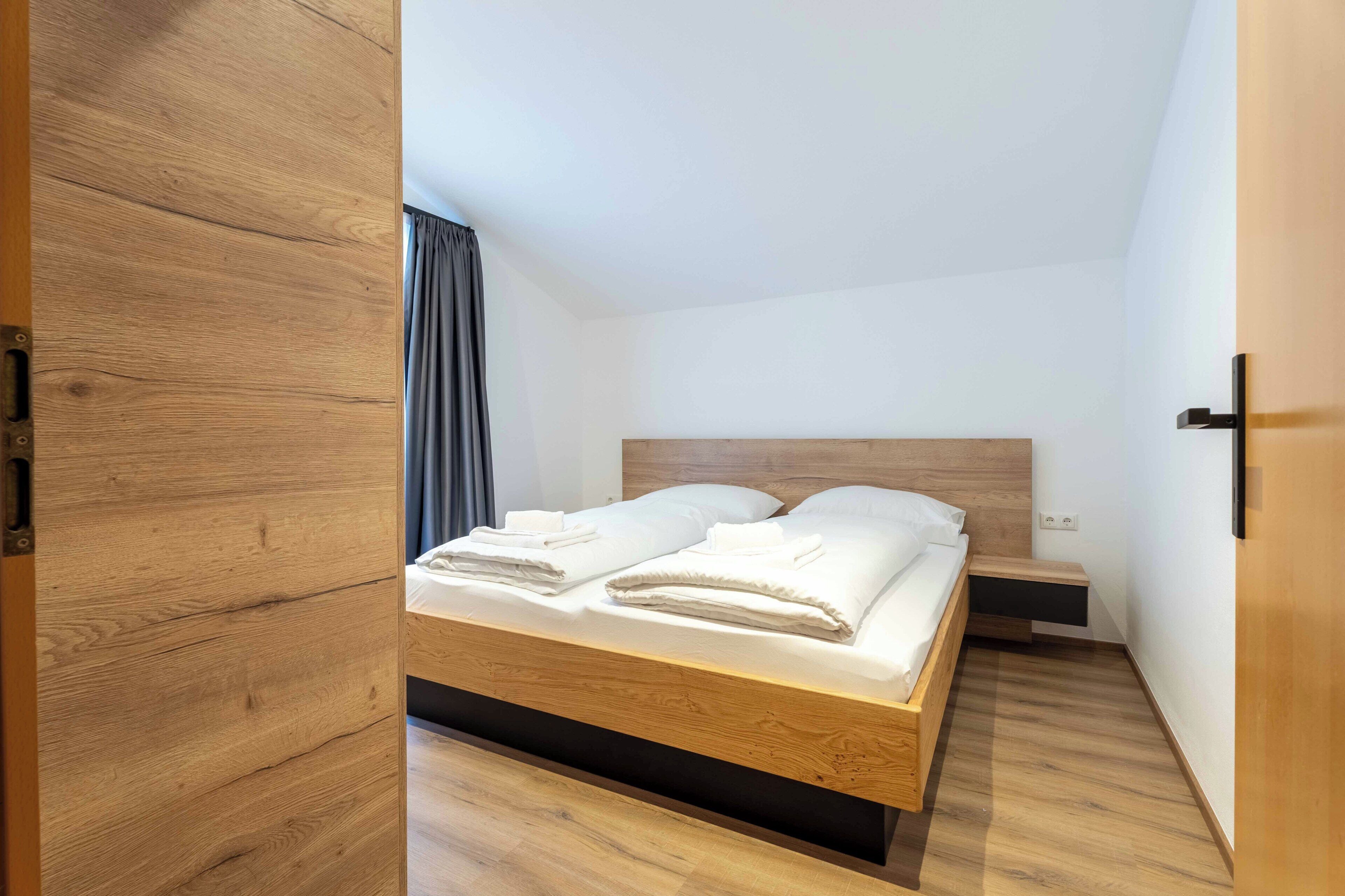 A modern bedroom with a wooden bed frame, a bedside table, and a nightstand.
