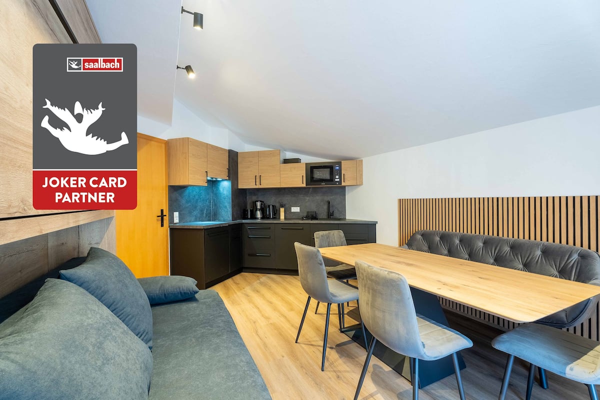 A modern kitchen with a microwave, wooden cabinets, and a dining area with a table and chairs.