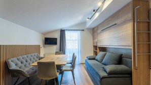 Una sala de estar moderna con una mesa de comedor de madera, un sofá capitonado y una televisión empotrada.