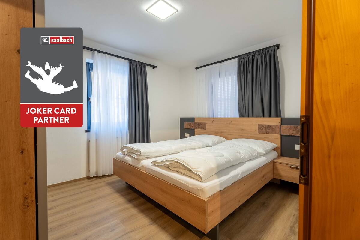 A room with a wooden bed, a nightstand, and a window with curtains.