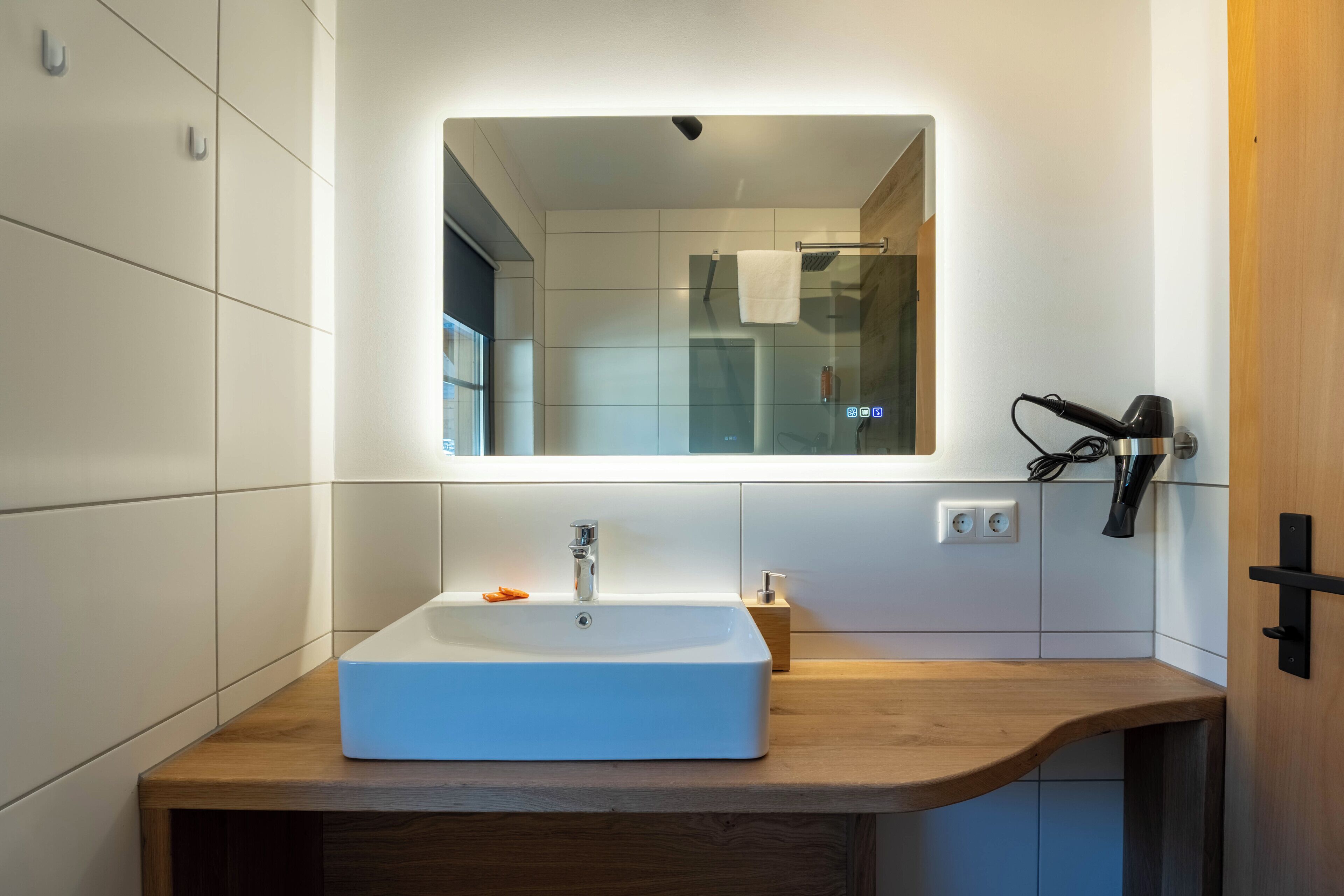 A modern bathroom with a rectangular sink, a mirror above it, and a towel rack to the right.
