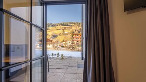 Una habitación con un ventanal, cortina y vistas a un paisaje nevado con edificios.