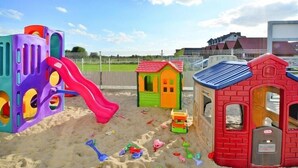 A playground with various play structures including a slide, a small house, and a brick playhouse. - Comfortable holiday homes with a summer pool (Jaroslawiec)