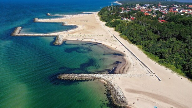 An aerial view of a coastal area with a beach, a pier, and a town in the background. - Comfortable holiday homes with a summer pool (Jaroslawiec)