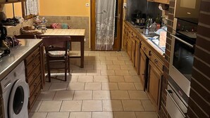 Une cuisine compacte équipée d’un lave-linge, d’une table à manger avec des chaises et d’un grand four.