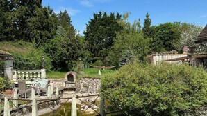 Un espace extérieur rustique agrémenté d’un pont de pierre, d’un petit étang et d’un bateau en bois.