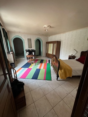Quarto com cama, cômoda, escrivaninha e tapete colorido.