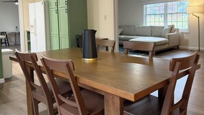 A dining area with a wooden table and chairs, a ceiling fan, and a kitchen in the background. - 3-bedroom House, Private Lake Access and Game Room (Hillsboro)