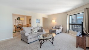 A living room with a sofa, armchair, coffee table, and a TV stand. - 🏖️Water Views | Steps to Beach | Beachfront Complex | Island Winds Penthouse 1 (Fort Myers Beach)