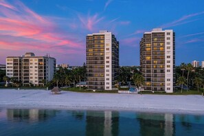 A beachfront hotel with multiple high-rise buildings, a pool, and palm trees. - 🏖️Water Views | Steps to Beach | Beachfront Complex | Island Winds Penthouse 1 (Fort Myers Beach)