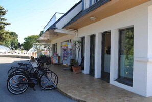A building with a covered entrance, bicycles parked outside, and a potted plant on the sidewalk. - ZEcamping 4 étoiles 200m plage piscine couverte mobil-home TV LV 30m2 (Névez)