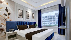 Une chambre d’hôtel moderne avec un grand lit, une table de chevet, une télévision et une fenêtre donnant sur la ville.