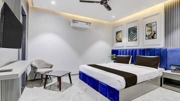 A modern hotel room with a bed, desk, chair, and ceiling fan.