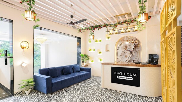 Un espace d’accueil avec un canapé bleu, un comptoir de réception portant l’inscription « Townhouse », et un sol à motifs.