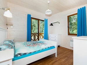 Ein Zimmer mit einem Bett, einem Schminktisch, einem Schreibtisch und einem Fenster mit Vorhängen.