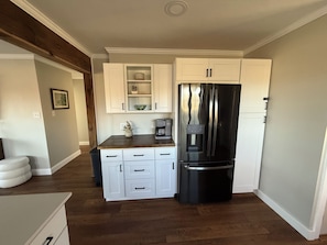 Una cocina compacta con armarios blancos, un refrigerador negro y una encimera de madera.