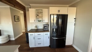 A compact kitchen with white cabinetry, a black refrigerator, and a wooden countertop. - Pa’s House is an enjoyable, entirely remodeled, 2-bedroom farmhouse near Anna. (Anna)