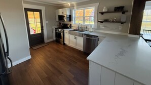 A modern kitchen with white cabinets, stainless steel appliances, and a large window providing natural light. - Pa’s House is an enjoyable, entirely remodeled, 2-bedroom farmhouse near Anna. (Anna)