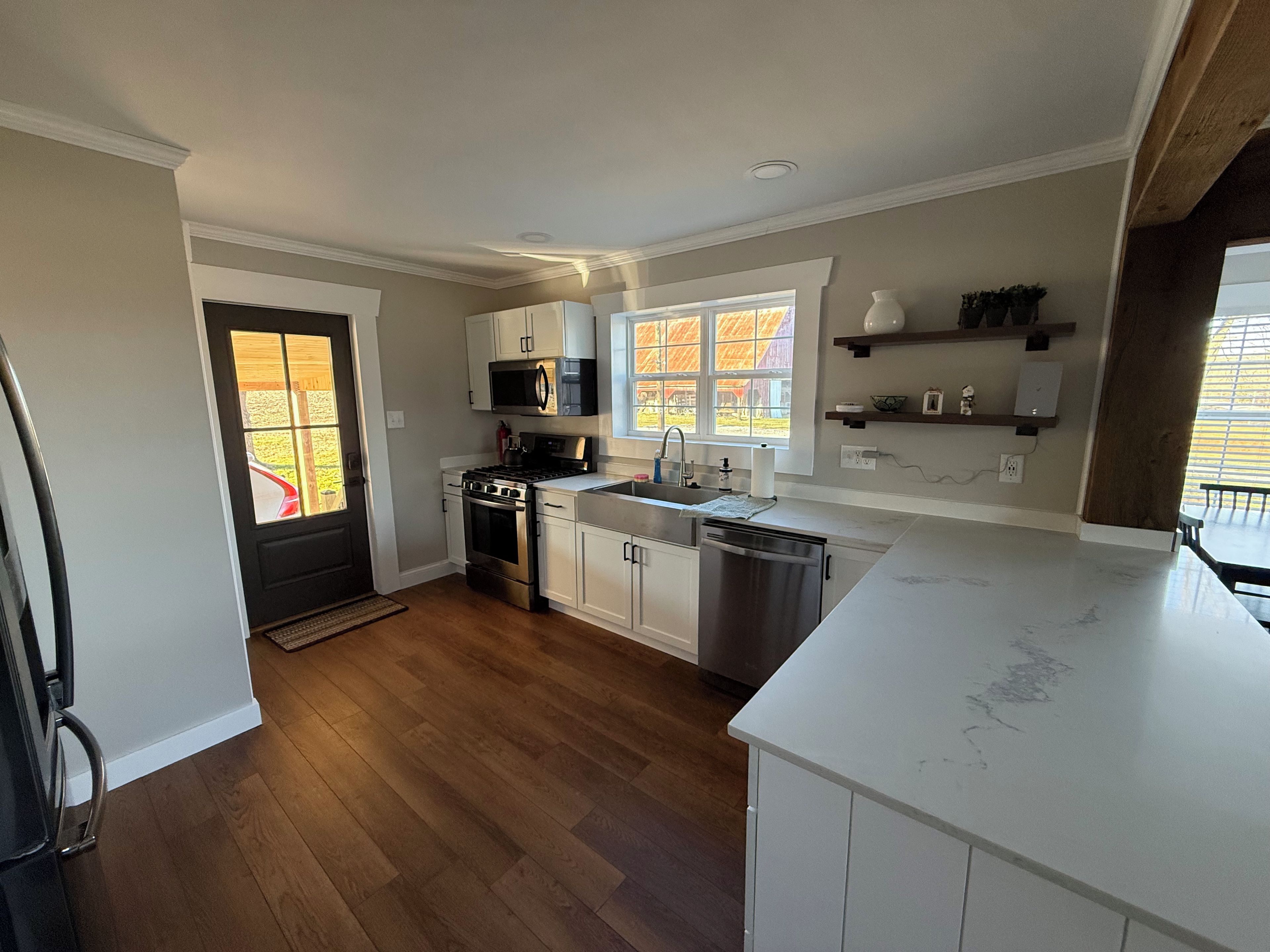 Una cocina moderna con armarios blancos, electrodomésticos de acero inoxidable y piso de madera.