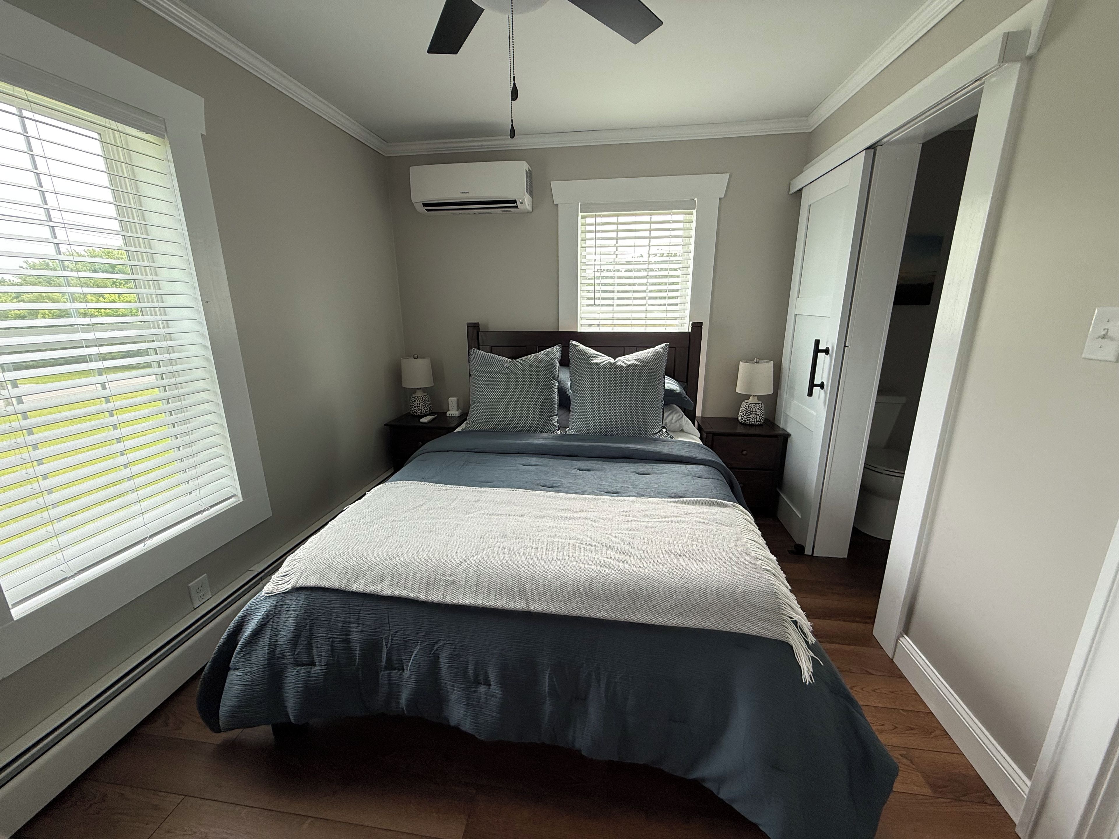 Een slaapkamer met een bed, nachtkastjes, een plafondventilator en een airconditioning.