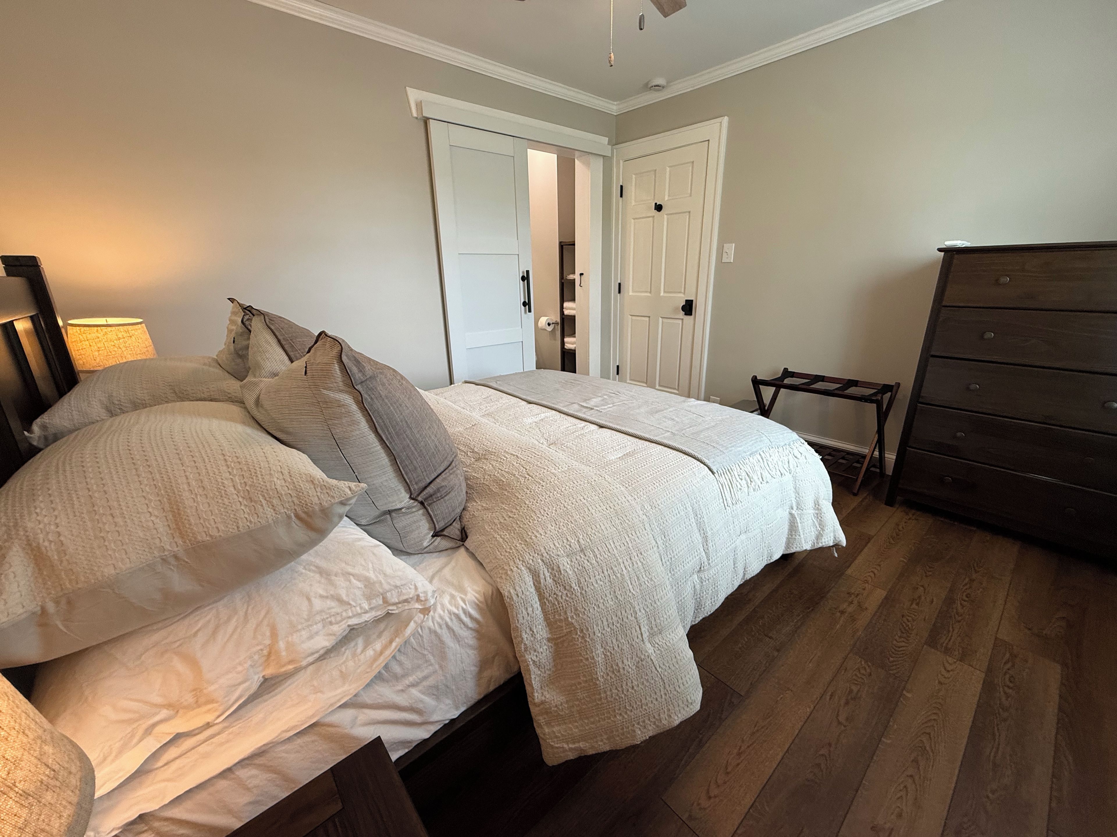 A bedroom with a bed, a dresser, and a door.