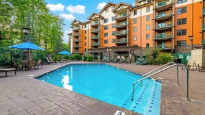 A swimming pool with a lifeguard stand, lounge chairs, and umbrellas. - 🌄 Baskins Creek 110 - Private Balcony - Fireplace - Steps to Downtown 🏔 (Gatlinburg)