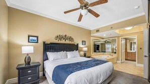 A bedroom with a bed, nightstand, lamp, ceiling fan, and a bathroom with a sink and mirror. - 🌄 Baskins Creek 110 - Private Balcony - Fireplace - Steps to Downtown 🏔 (Gatlinburg)