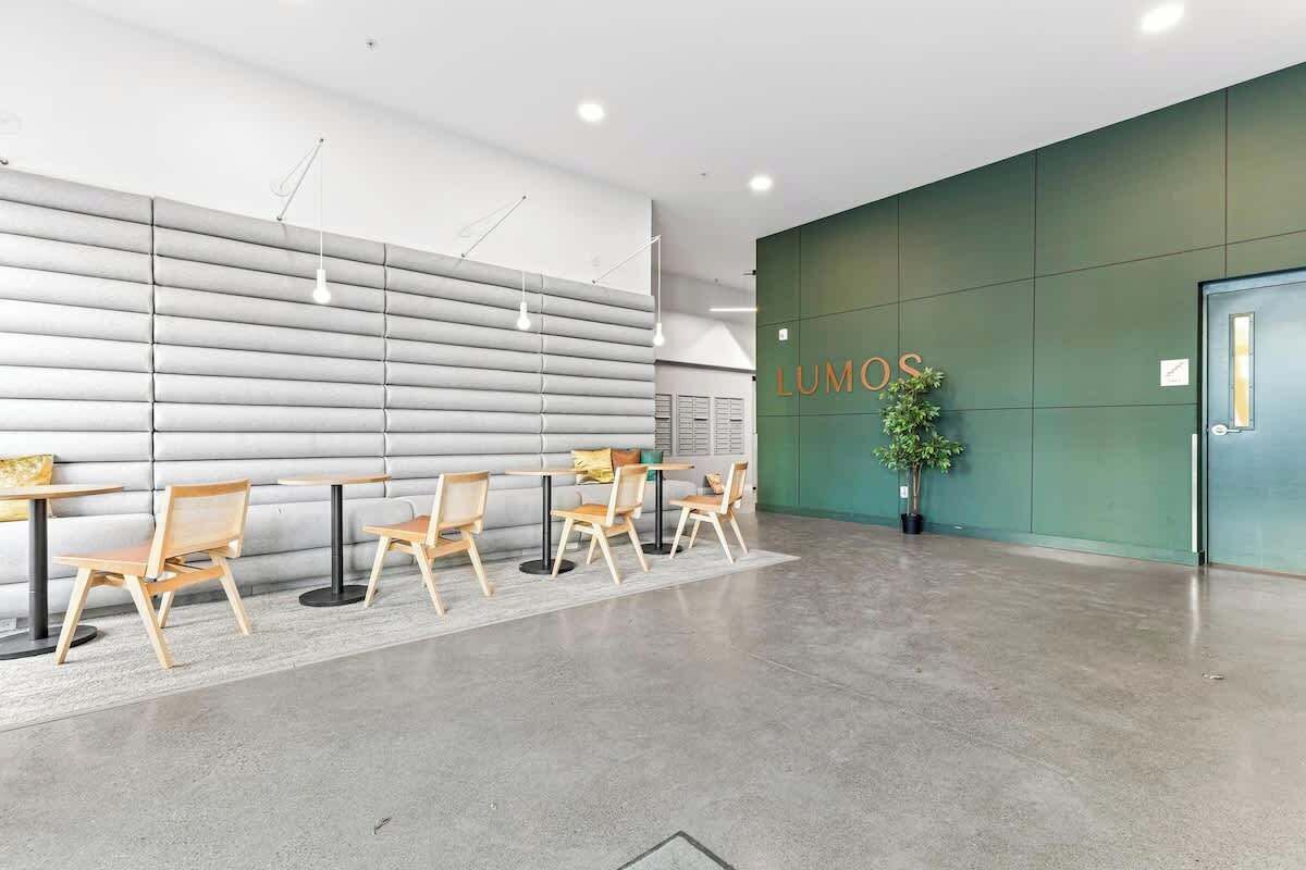 A modern interior with a reception desk, seating area, and a green accent wall with the word 'LUMOS'.