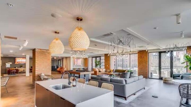 A modern kitchen with a central island, a dining area with a round table, and a living space with a sofa and a coffee table. - Studio to Downtown w Rooftop (Cincinnati)