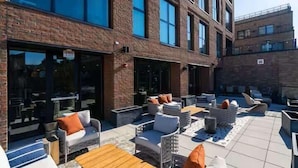 A rooftop patio with outdoor seating, a brick building, and large windows. - Studio to Downtown w Rooftop (Cincinnati)