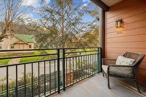 Ein Balkon mit einem Korbstuhl und einer Wandleuchte.