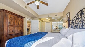 A bedroom with a bed, wooden wardrobe, ceiling fan, and a bathroom visible through an open door. - Baskins Creek 111 🌲 Welcoming Retreat | Pool, Hot Tub & Fireplace ✨ (Gatlinburg)