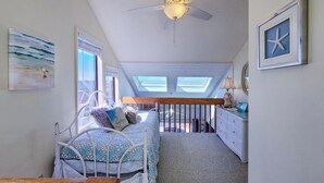 Un dormitorio con cama, ventilador de techo, cómoda y ventana.