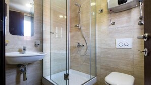 Ein modernes Badezimmer mit einer Duschkabine, einem weißen Waschbecken und einer Toilette.