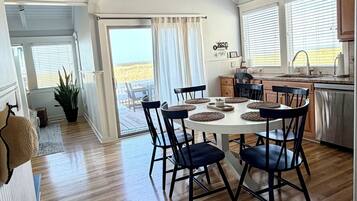 Un intérieur spacieux de style loft comprenant un coin repas, une cuisine et de grandes fenêtres offrant une vue dégagée.