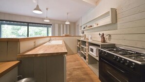 Uma cozinha moderna com bancada de madeira, eletrodomésticos de aço inoxidável e iluminação pendente.