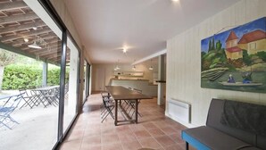 Uma sala espaçosa com uma mesa de jantar, um sofá e uma cozinha ao fundo.