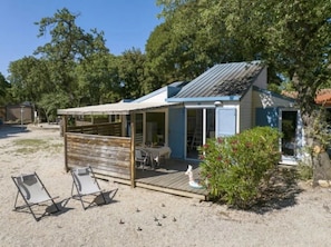 A small wooden structure with a covered patio, a table, and chairs outside.