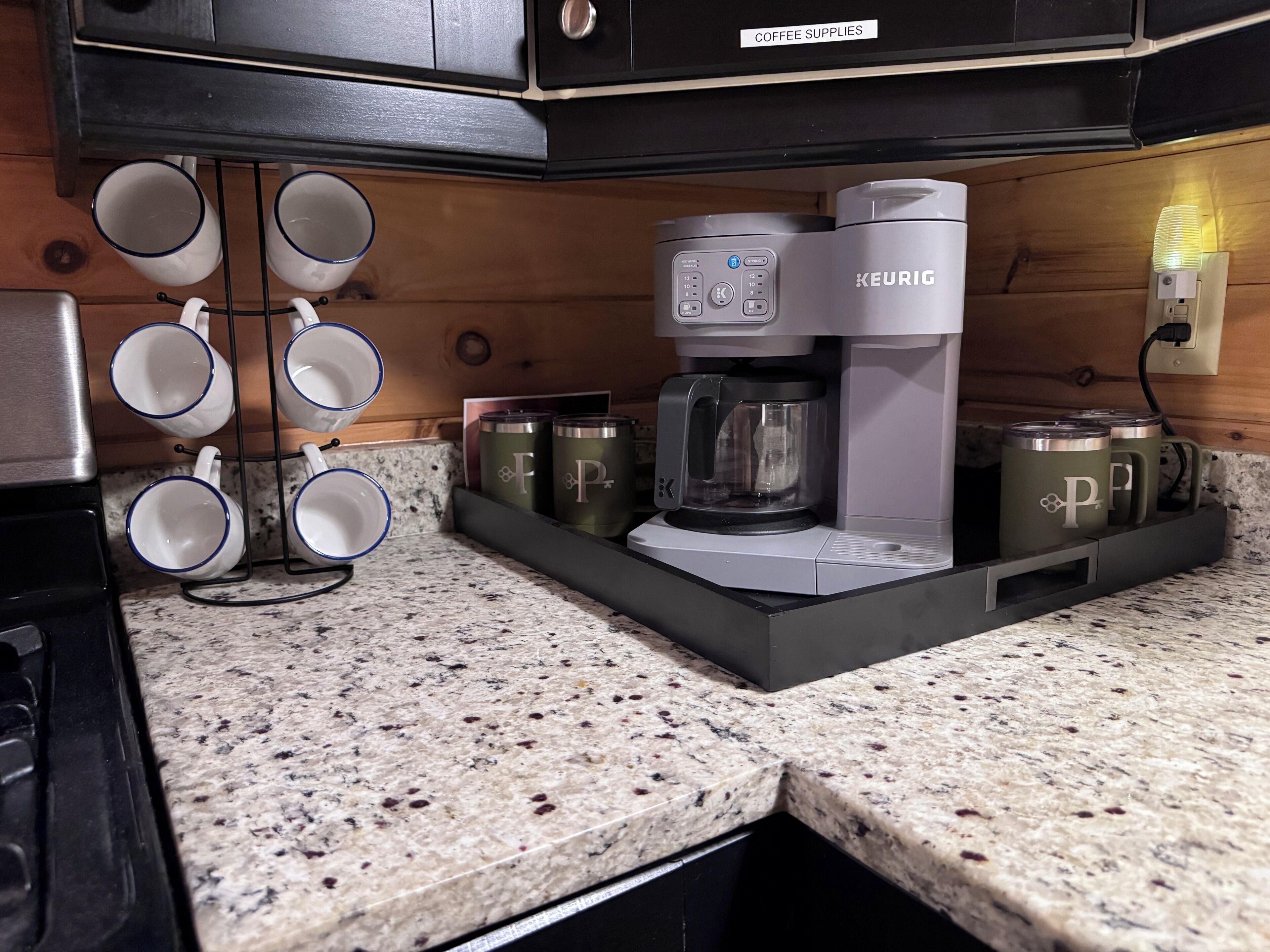 A kitchen with a Keurig coffee maker, a mug rack, and storage containers.
